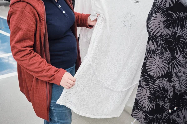 Έγκυος γυναίκα στο κατάστημα επιλέγει ένα χαλαρό, λευκό, δαντέλα και διαφανές φόρεμα — Φωτογραφία Αρχείου