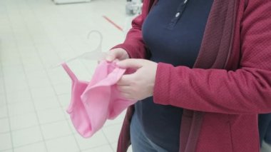 Hamile kadın pembe elbiseler seçiyor - mağazadan bir bebek için korse.