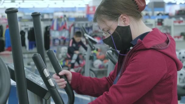 Frau im Sportgeschäft wählt großen Sportsimulator - Laufband zu kaufen — Stockvideo