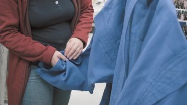 Mağazadaki kadın güreş için mavi kimono almayı seçiyor. Eller yakın çekim