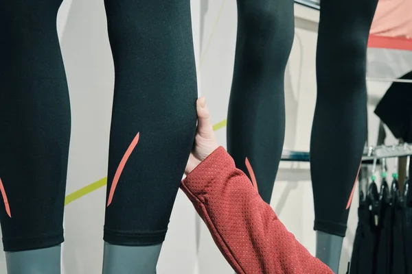 Mulher em uma loja de esportes escolhe leggings apertados e sintéticos para correr para comprar — Fotografia de Stock