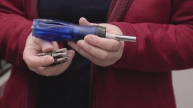 İnşaat malzemeleri mağazasında çalışan bir kadın yerine konulabilir eklentileri olan bir tornavida alıyor.