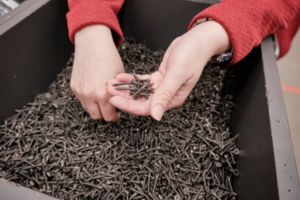 Woman in building materials store buys screws self tapping. Hands close up shot