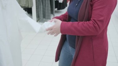 Dükkandaki hamile kadın kocası için yeni bir beyaz iş gömleği seçiyor.