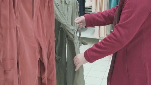 Caucasian pregnant woman in the store buys a spacious dress of light green color — Stock Video