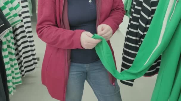 Zwangere vrouw kiest losse groene broek met witte strepen in petto om te kopen — Stockvideo