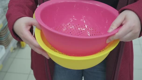 Fille dans le magasin choisit une grande passoire en plastique pour la cuisine — Video