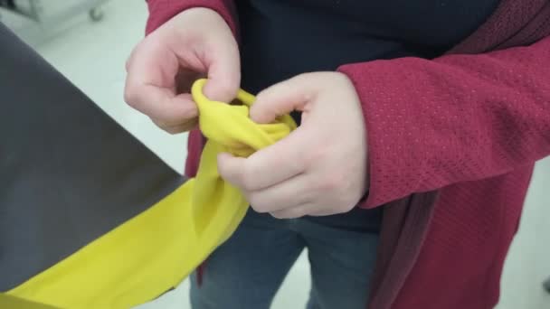 Kobieta w sklepie kupuje żółtą szarą bluzę. Starannie bada wyroby włókiennicze — Wideo stockowe
