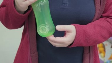 Hamile kız doğmamış bebeği beslemek için emziği olan bir şişe seçiyor.