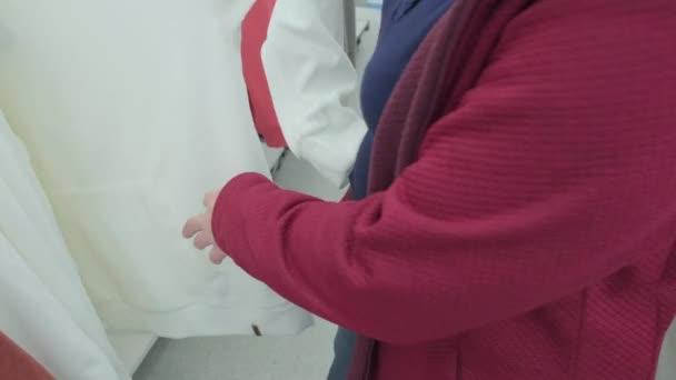 Übergewichtige Frau kauft in einem Geschäft ein weißes Sweatshirt. Hände aus nächster Nähe — Stockvideo