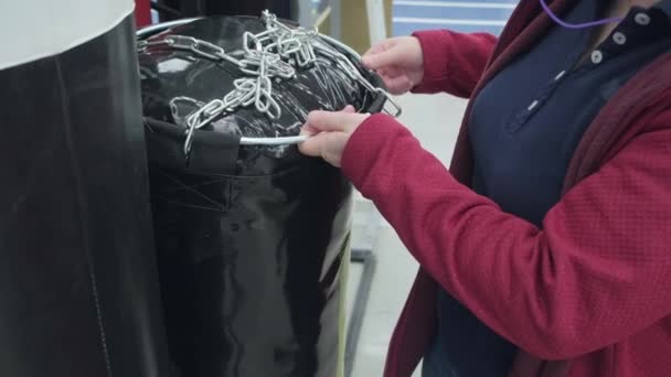 Vrouw in een winkel koopt een grote, zwarte peer voor boksen en vechtsport — Stockvideo