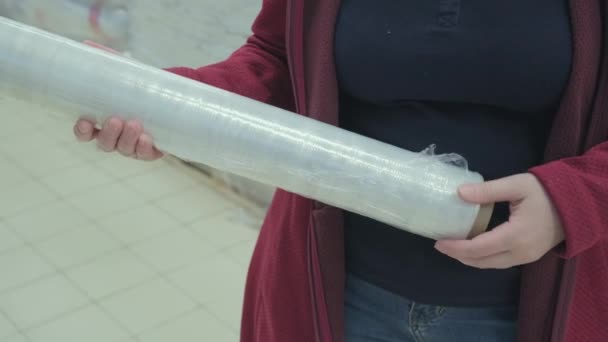 Mulher em uma loja compra um envoltório de plástico para embalagens de produtos e coisas — Vídeo de Stock