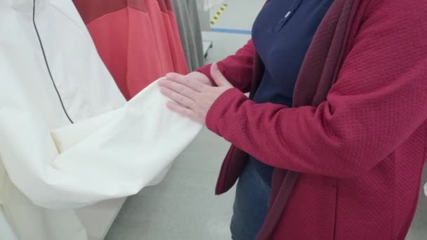 Pregnant woman buys a white zip up jacket in a store. Hands close up — Stock Video