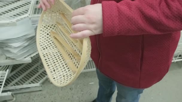 Кавказская девушка покупает в магазине деревянные плетеные хлебные тарелки с деревянными щипцами — стоковое видео