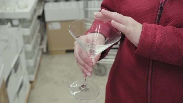 Кавказская девушка покупает большое прозрачное стекло для мартини и коктейлей в магазине — стоковое видео