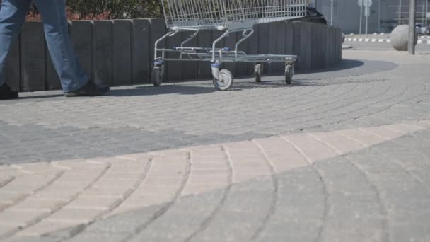 Chica en la calle toma un carrito de comestibles de pie junto a un gran centro comercial — Vídeo de stock