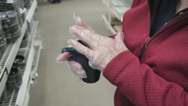 Blank meisje in handschoenen tegen virus koopt blauwe mok voor warme dranken in de winkel — Stockvideo