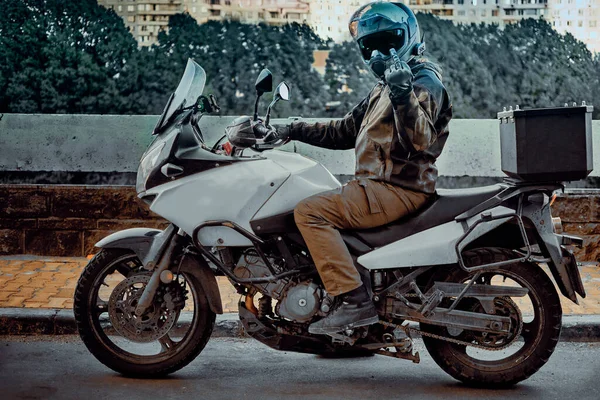 O motociclista faz um gesto obsceno com o dedo médio. Nele um capacete de espelho — Fotografia de Stock