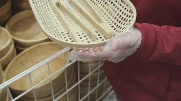 Menina em luvas contra vírus compra pratos de pão de vime com pinças de madeira na loja — Vídeo de Stock