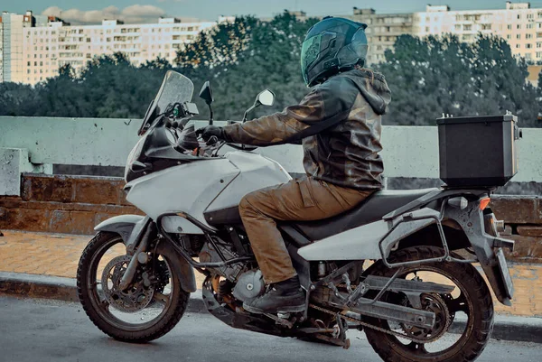 Motociclista em um capacete espelho em uma motocicleta enferrujada em um ambiente urbano — Fotografia de Stock