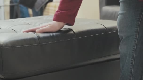 Caucasian woman in the store chooses for buy an ottoman made of brown leather — Stock Video