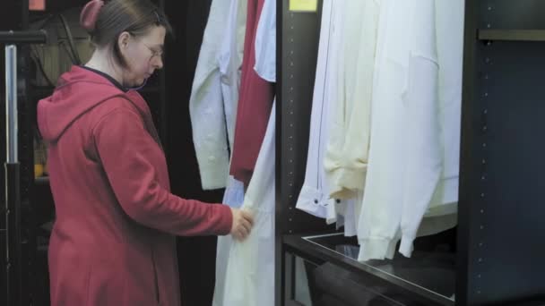 Mujer caucásica en una tienda compra ropa. Concepto de moda y estilo — Vídeos de Stock