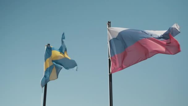 Bandeiras da Suécia e da Federação Russa agitam-se no vento contra o céu azul — Vídeo de Stock