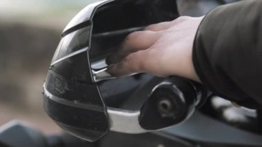 Motorcunun sol eli, bir motosikletin debriyaj kolunu sıkıştırıyor. Yakın çekim.
