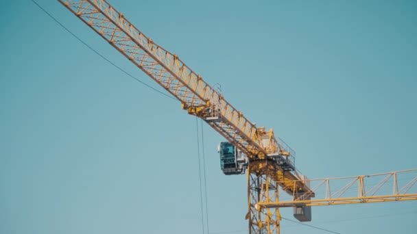 Yellow boom of the crane turns from left to right against the blue sky — Vídeo de stock