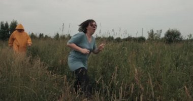 Woman runs away from a maniac with an axe in a yellow raincoat with a hood