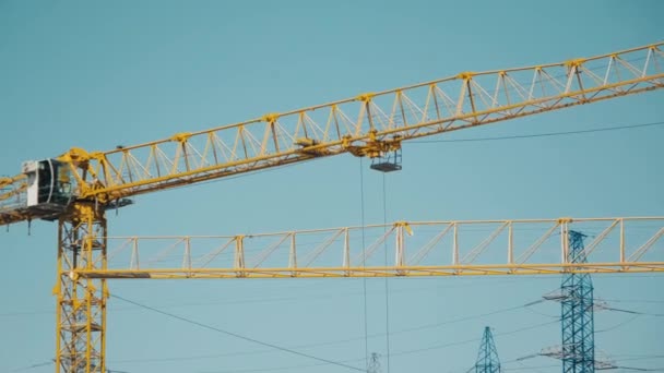 Gele mast van de kraan draait van rechts naar links tegen de blauwe lucht — Stockvideo