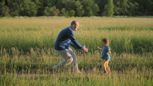 Der junge Vater rennt die Straße entlang, um seine kleine Tochter zu treffen. Sommer und Sonnenuntergang — Stockvideo