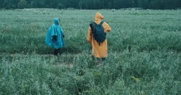 Homem e mulher em capas impermeáveis estão envolvidos em caminhadas e discussões sobre novas rotas — Vídeo de Stock