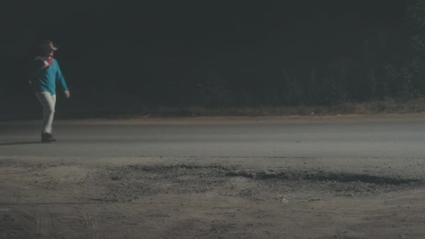 L'homme au chapeau de cow-boy marche le long de la nuit, route brumeuse. Concept de voyage, randonnée — Video