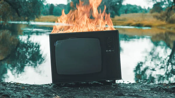 Η παλιά ρετρό τηλεόραση καίγεται δίπλα σε μια λίμνη. Έννοια της μετά την αποκάλυψη, σουρεαλισμός — Φωτογραφία Αρχείου