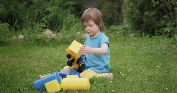 Bebê bonito está brincando com um kit de construção e um trator de brinquedo — Vídeo de Stock