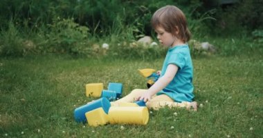 Küçük, güzel bir çocuk oyuncak buldozer ve inşaat setiyle oynuyor.