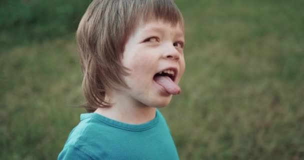 Malé, hezké dítě ukazuje jazyk a dělá obličeje. Uzavření portrétu — Stock video