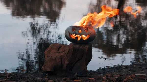 Halloween. Kürbis auf Teich-Hintergrund, es glüht, feurige Flamme brennt darin — Stockfoto