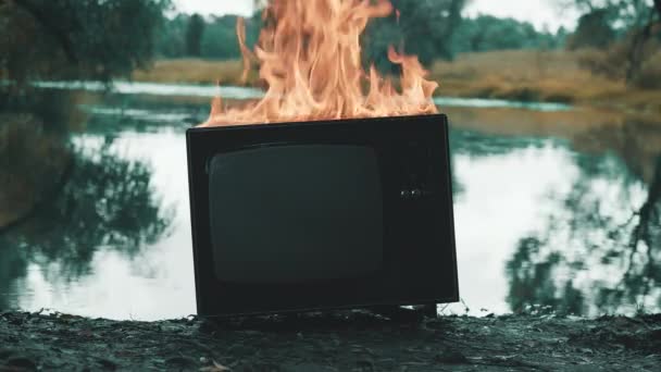 旧的复古电视机在池塘边着火了。启示录后的概念，超现实主义 — 图库视频影像