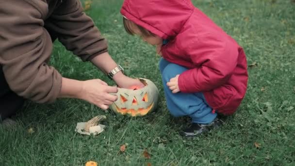 Mama und ein süßes kleines Mädchen zünden Kerzen in einem Kürbis für Halloween an — Stockvideo