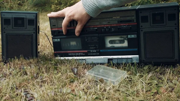 Der er en retro båndoptager på græsset. Mennesket justerer lyden på enheden Stock-billede