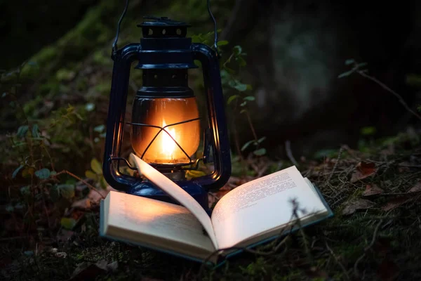 Bir gaz lambası ve karanlık ormanda bir kitap.