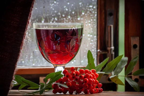 Yağmurlu bir günde pencere eşiğinde bir kadeh kırmızı şarap