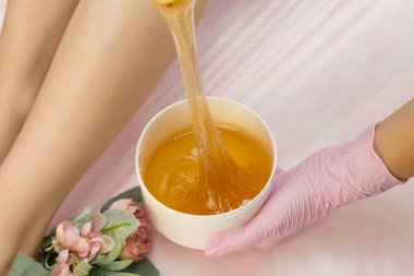 Lüks bir spa stüdyosunda saç kesimi. Kadınların ayakları sakarinle ağda yapar. Sıcak şeker. Balmumu kasesinin ürünü. Salon bankasında. Mor, eflatun arkaplan