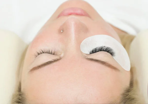 Eyelashes extensions. Fake Eyelashes. Eyelash Extension Procedure. Professional stylist lengthening female lashes. Master and a client in a beauty salon