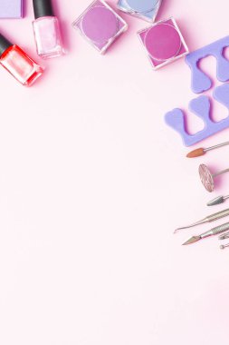 Pembe ve mor arka planda manikür ve pedikür için kozmetik seti. Jel cilası, tırnak törpüsü, tırnak makası, satıcı, boşluk açıcılar ve tel kesiciler. Metin için yeri olan bir kartpostal kompozisyonu