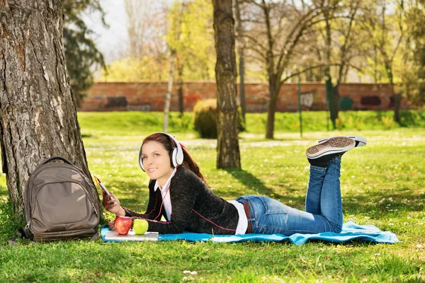 Hermosa estudiante escuchando música en el parque — Foto de Stock