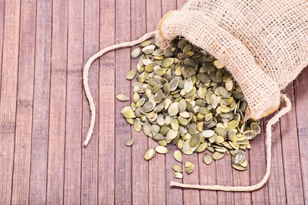 Semillas de calabaza derramadas sobre fondo de madera — Foto de Stock