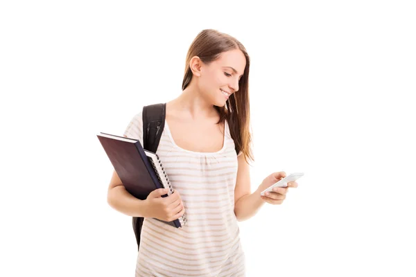 Lachende student met leerboeken die haar telefoon controleert — Stockfoto